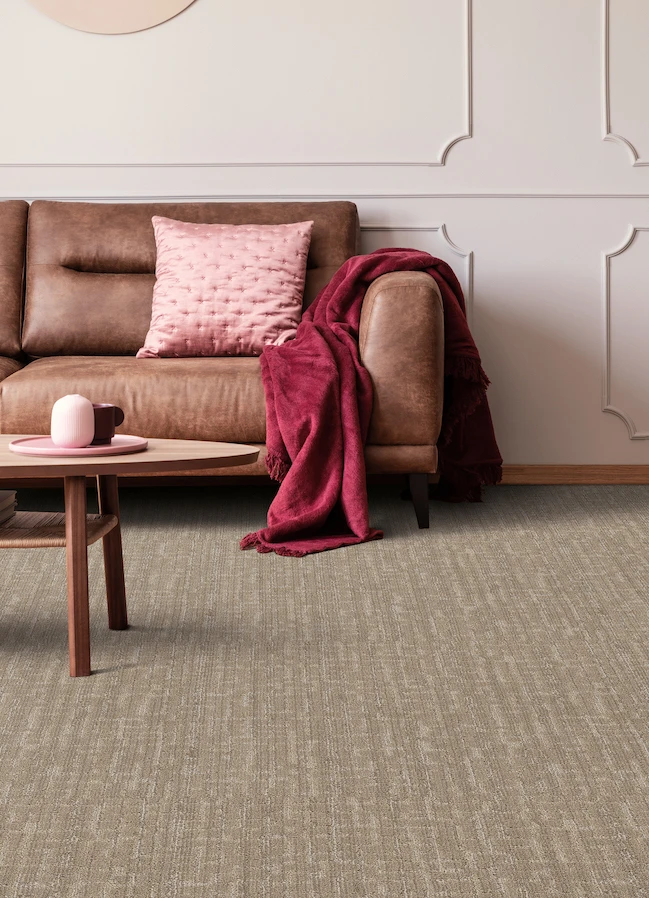 durable textured brown carpets in a modern living room with brown leather couch and pink accents